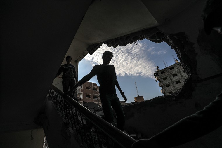 Image: Palestinians look at a damaged building after an Israeli airstrike in Gaza City