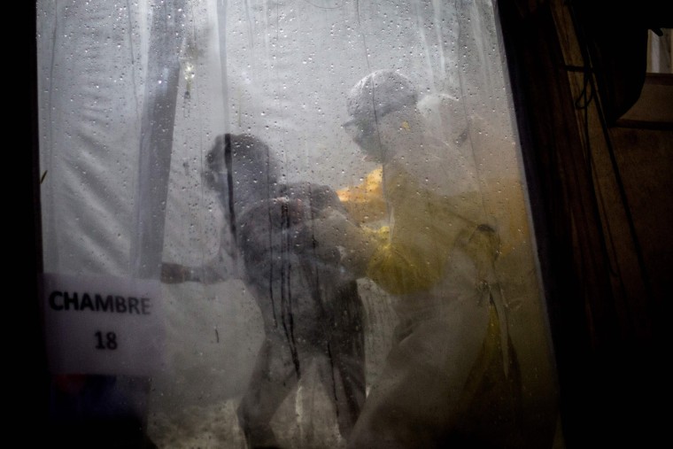 Health workers help an unconfirmed Ebola patient into her bed inside a Doctors Without Borders Ebola treatment center on Nov. 3, 2018.