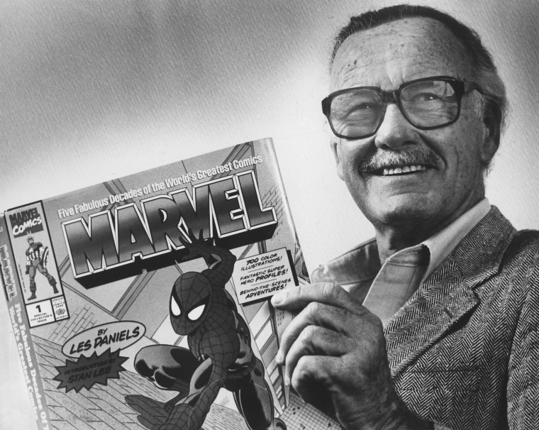 Marvel Comics publisher Stan Lee poses with a book of \"Spider Man\" comics
