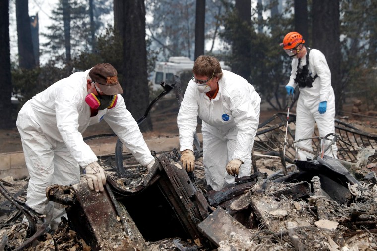 Image: A volunteer search and rescue crew from Calaveras County comb through a home destroyed by the Camp Fire in Paradise