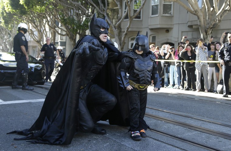 Miles Scott, dressed as Batkid, walks with Batman before saving a damsel in distress in San Francisco on Nov. 15, 2013.