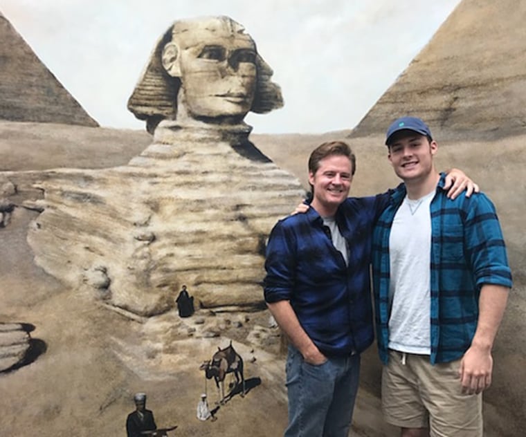 Michael Rubino, left, stands beside his biological son Nathan Mayes in front of a mural the two painted together. Despite opposing views on politics and religion, the two have a tight bond.