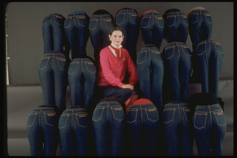 Gloria Vanderbilt sits with models wearing jeans from her denim line.