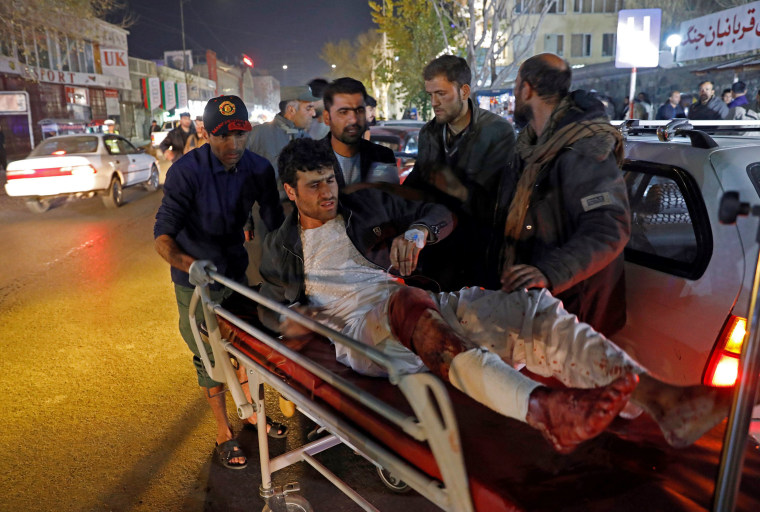 Image: Men carry an injured person to a hospital after a suicide attack in Kabul, Afghanistan