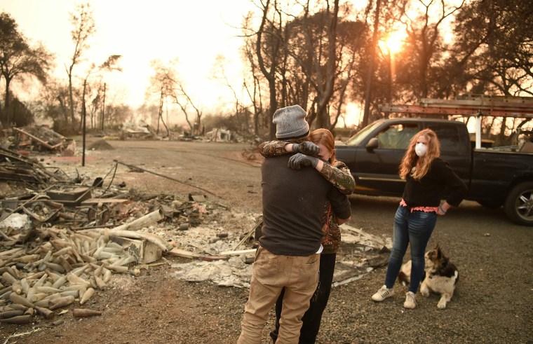 Image: Kimberly Spainhower hugs her husband Ryan Spainhower while their daughter Chloe Spainhower, 13, looks on at the burned remains of their home in Paradise, California on Nov. 18, 2018.