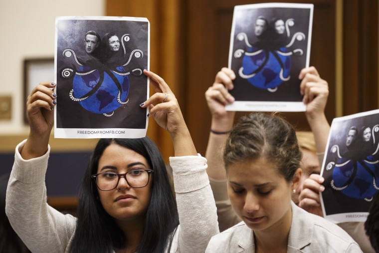 Demonstrators hold up signs protesting Facebook during a House Judiciary Committee hearing in Washington on July 17, 2018.