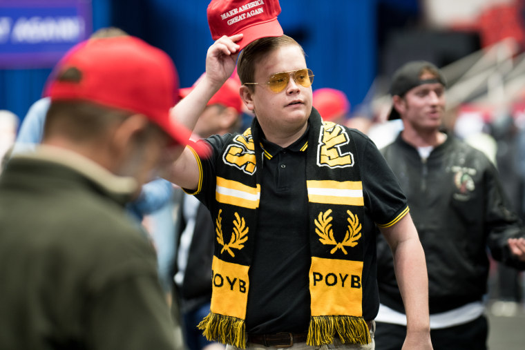 Image: A man wearing a Proud Boys scarf attends a rally for President Donald Trump