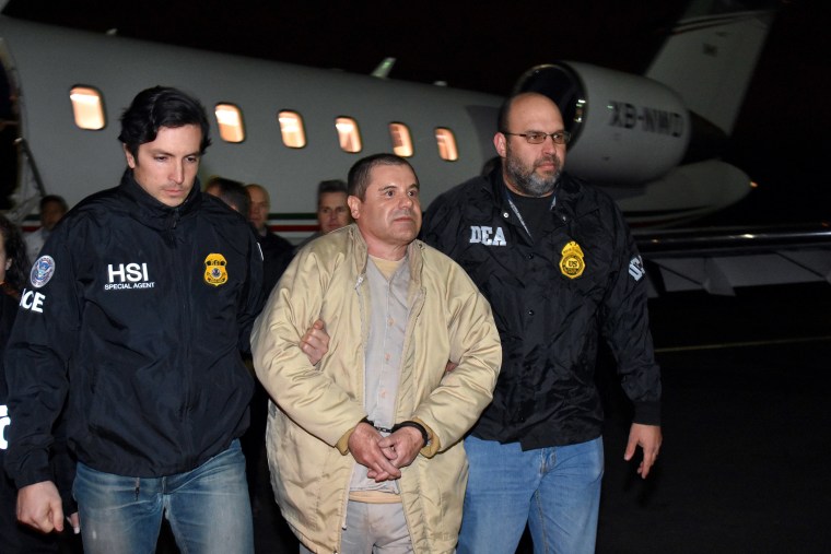 Image: Authorities escort Joaquin "El Chapo" Guzman, center, from a plane to a waiting caravan of SUVs at Long Island MacArthur Airport