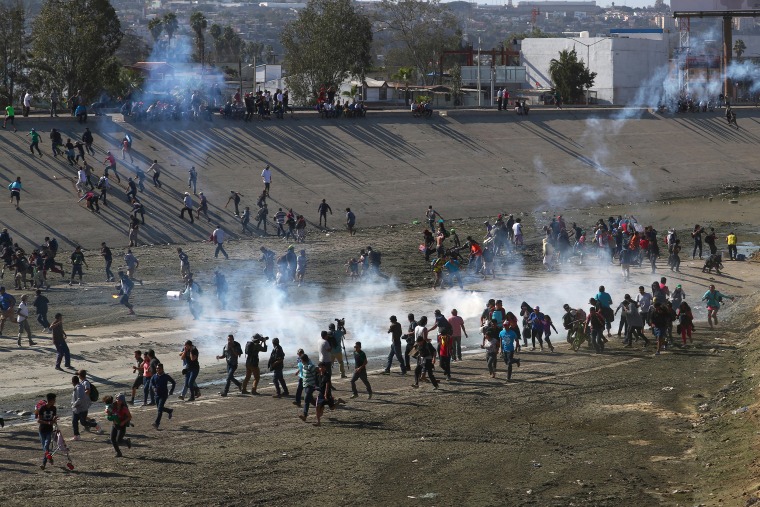Image: Migrants run from tear gas, thrown by the U.S border patrol, near the border fence between Mexico and the United States in Tijuana