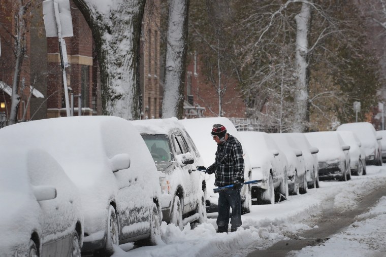 A resident of the Humboldt Park neighborhood in Chicago surveys a car after an early winter snowstorm dumped several inches of snow on Monday.