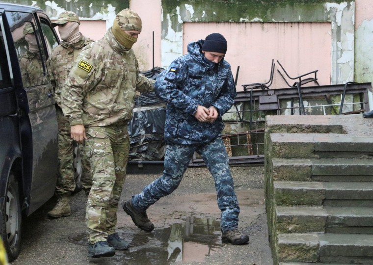 Image: A member of Russia's FSB security service escorts a detained Ukrainian navy sailor on Nov. 27