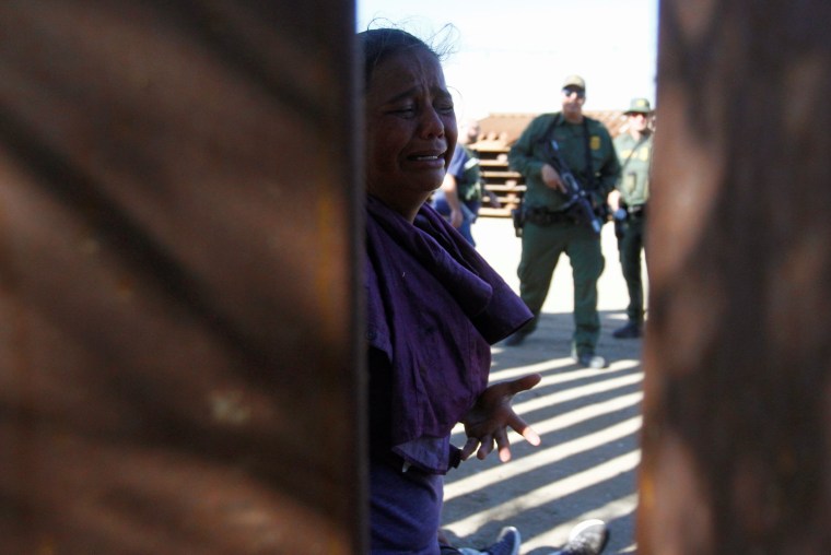 A migrant woman reacts as a group of border patrol officers detain her at the border in Tijuana, Mexico, on Nov. 25, 2018.