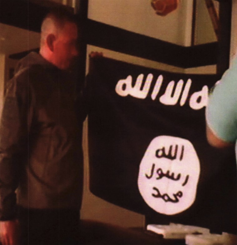 Army Sgt. 1st Class Ikaika Kang holds an Islamic State group flag after allegedly pledging allegiance to the group