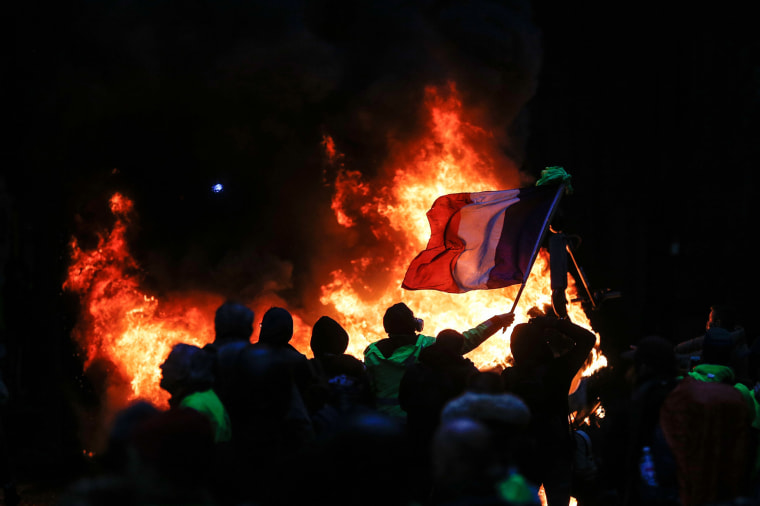 Image: Protestors fly a French flag during a protest of Yellow vests (Gilets jaunes) against rising oil prices and living costs