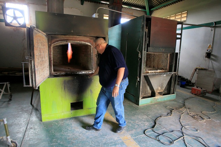 Image: A worker sets a crematory oven up at Eden Gardens cemetery in Maracaibo