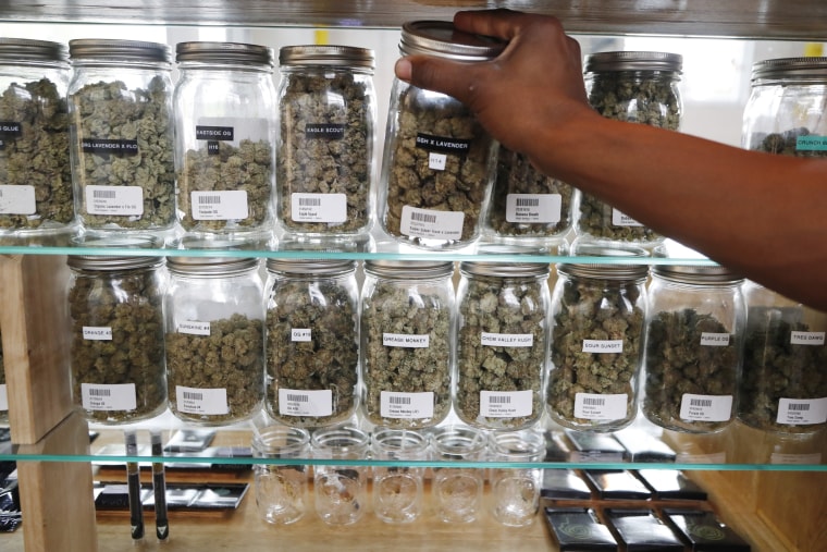 A clerk reaches for a container of marijuana buds for a customer at Utopia Gardens, a medical marijuana dispensary, in Detroit, on Oct. 2, 2018.