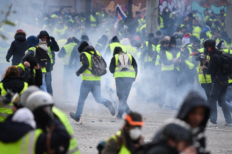 Image: Protesters run through tear gas in Paris on Saturday