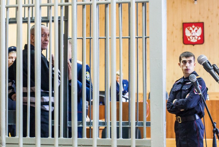 Mikhail Popkov stands inside a defendant's cage during a court hearing in Irkutsk