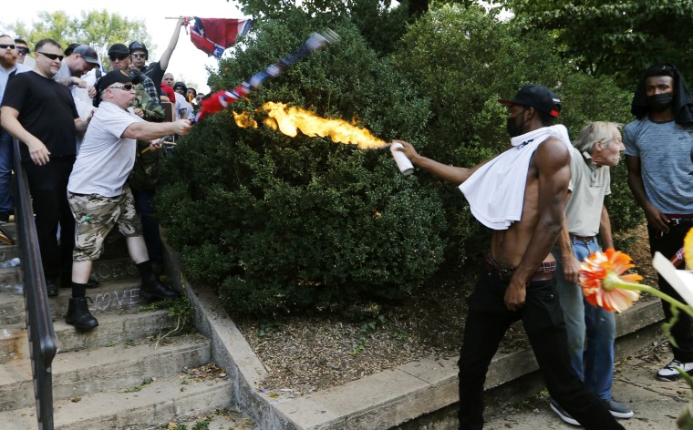 Image: A counter demonstrator uses a lighted spray can against a white nationalist demonstrator