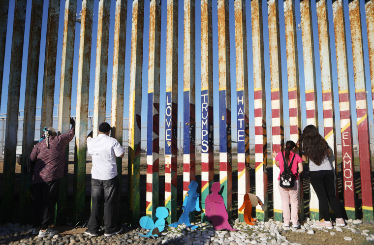 Image: Fernanda and Evelyne Lopez, right, speak with their father standing in San Diego on the other side of the border fence in Tijuana, Mexico, on Dec. 15, 2018.