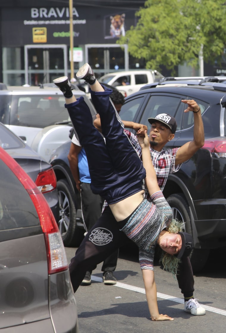 Image: Maria Molina, upside down, and Miguel Angel Flores break dance for tips from commuters in Lima, Peru, on Dec. 12, 2018.