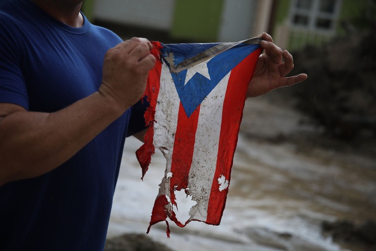 Image: Jose Javier Santana holds a Puerto Rican flag he found after Hurricane Maria passed through Utuado on Oct. 6, 2017.
