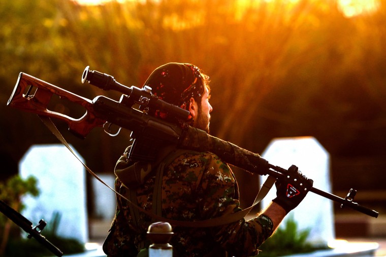 Image: A fighter with the Syrian Democratic Forces holds a rifle as he attends a funeral