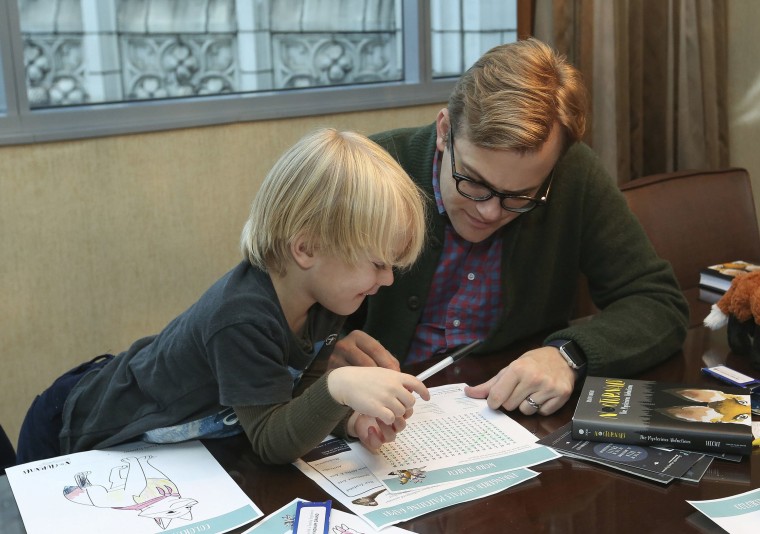 Image: Adam Bryan and his son Wesley work together on puzzles included in complimentary backpacks provided with other incentives by the Wyndham Grand Hotel in Chicago