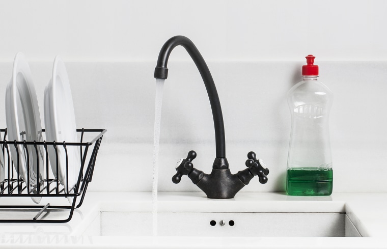 A sink, water tap and dish soap in a kitchen.