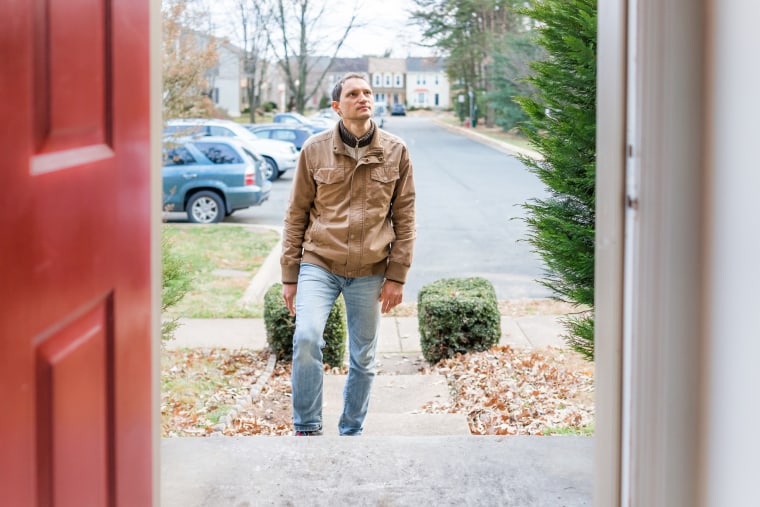 Young man standing on front porch of home in winter