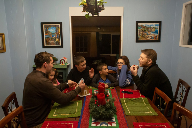 From left, Justin McNeil, along with his kids, Daisy, 6, and Kirby, 12, Frank, 9, and his wife Niki McNeil, make a gingerbread house with family friend Vince Villano at the McNeil home in DuPont, Washington. (Photo by David Ryder)