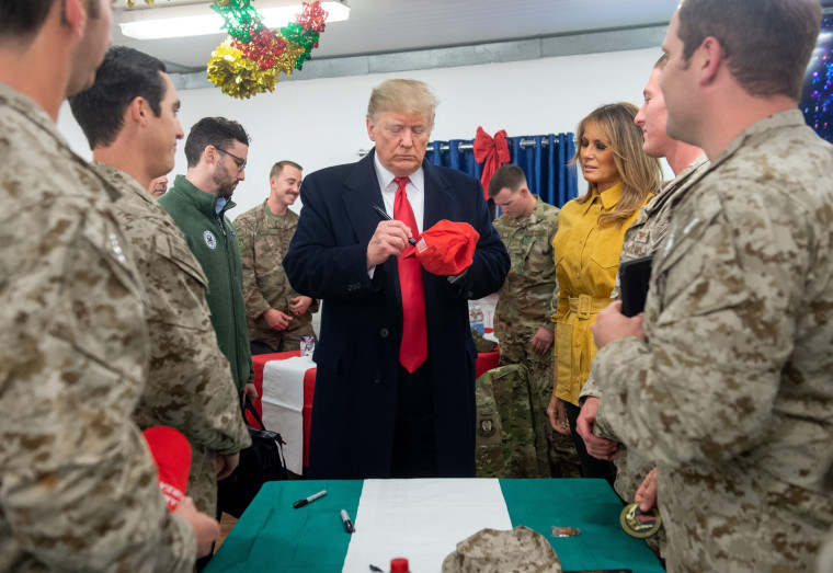 Image: President Donald Trump signs a hat at Al Asad Air Base in Iraq.