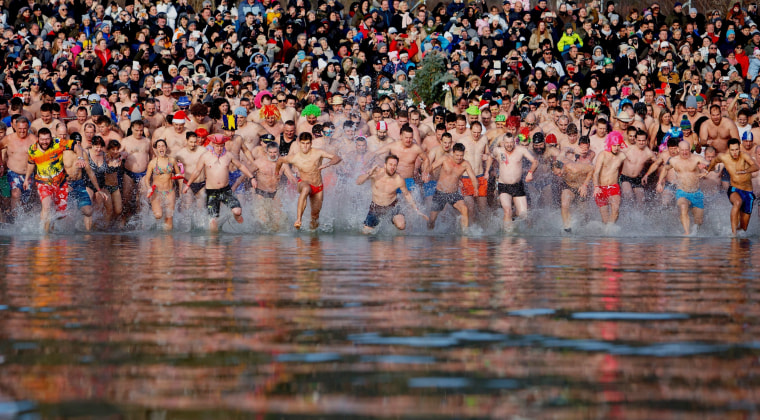 Image: Swimmers run into the chilly waters of Lake Balaton in Szigliget, Hungary.