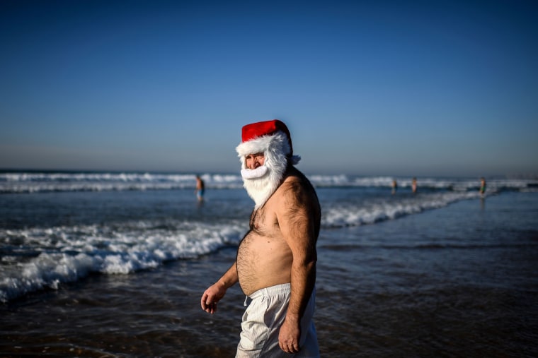 Image: \"Santa Claus\" treads the shore as others take the traditional dip to welcome the new year at Carcavelos Beach in Lisbon, Portugal.