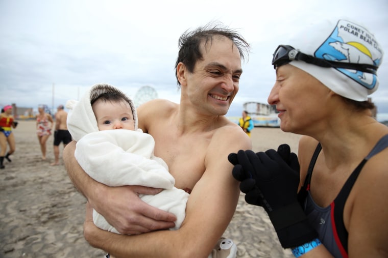 Image: A man holds a baby before the annual Coney Island Polar Bear Club New Year's Day Plunge in Brooklyn, New York.