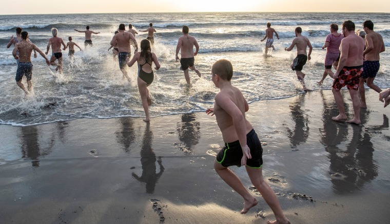 Image: Swimmers run to the Baltic Sea for the traditional plunge at the port of Ystad, Sweden.
