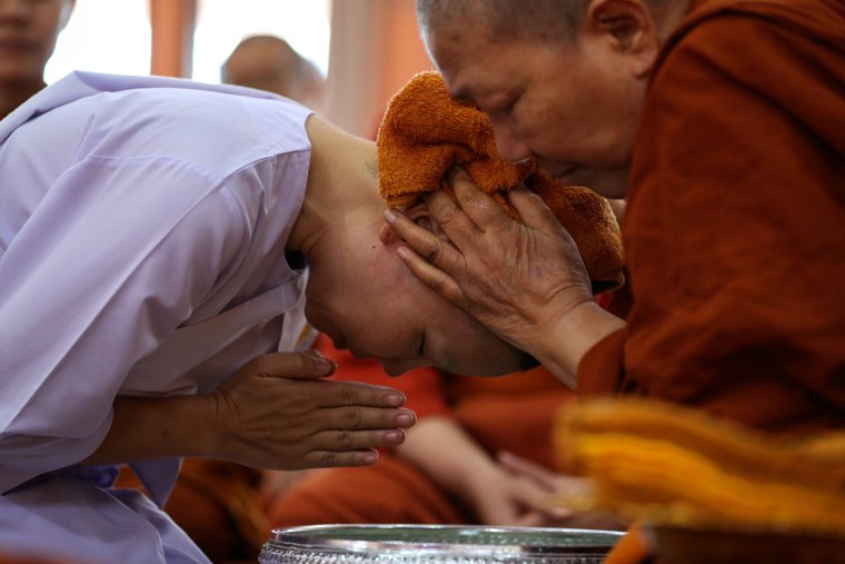 Image: A devotee who ended her novice monkhood has her head cleaned by the abbess at the Songdhammakalyani monastery
