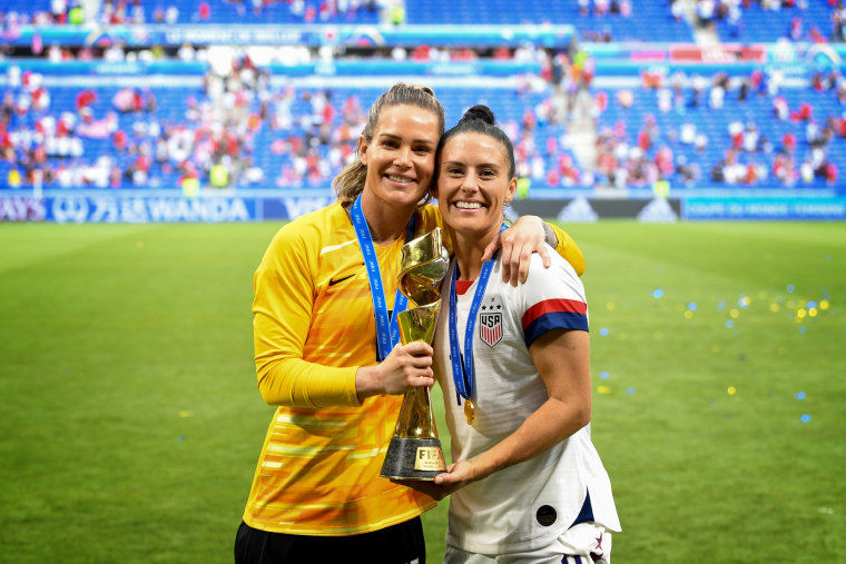 Image: Ashlyn Harris and Ali Krieger pose with the World Cup trophy after the United States defeated the Netherlands in the FIFA Women's World Cup on July 7, 2019.