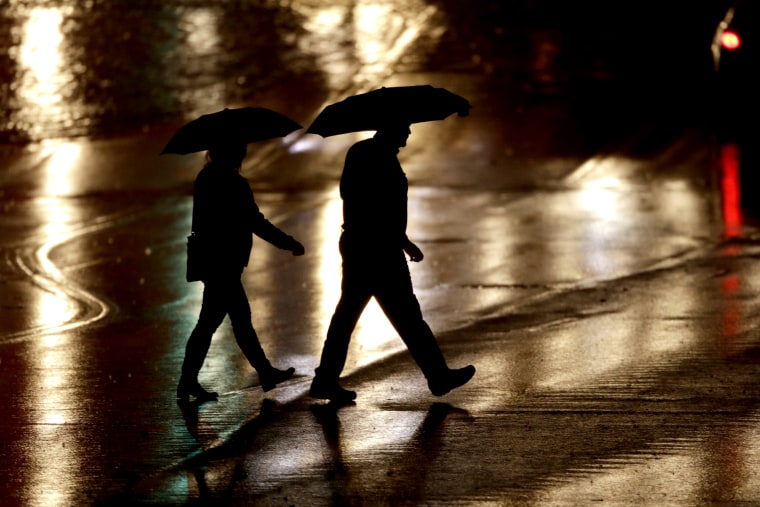 Image: Pedestrians cross a rain-covered street during a series of strong storms in Kansas City, Mo., on Dec. 28, 2019.