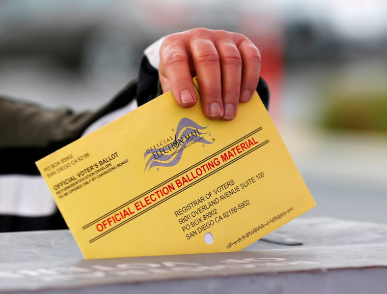 Image: A poll worker places a mail in ballot into a voting box as voters drop off their ballot in the U.S. presidential primary election in San Diego, California