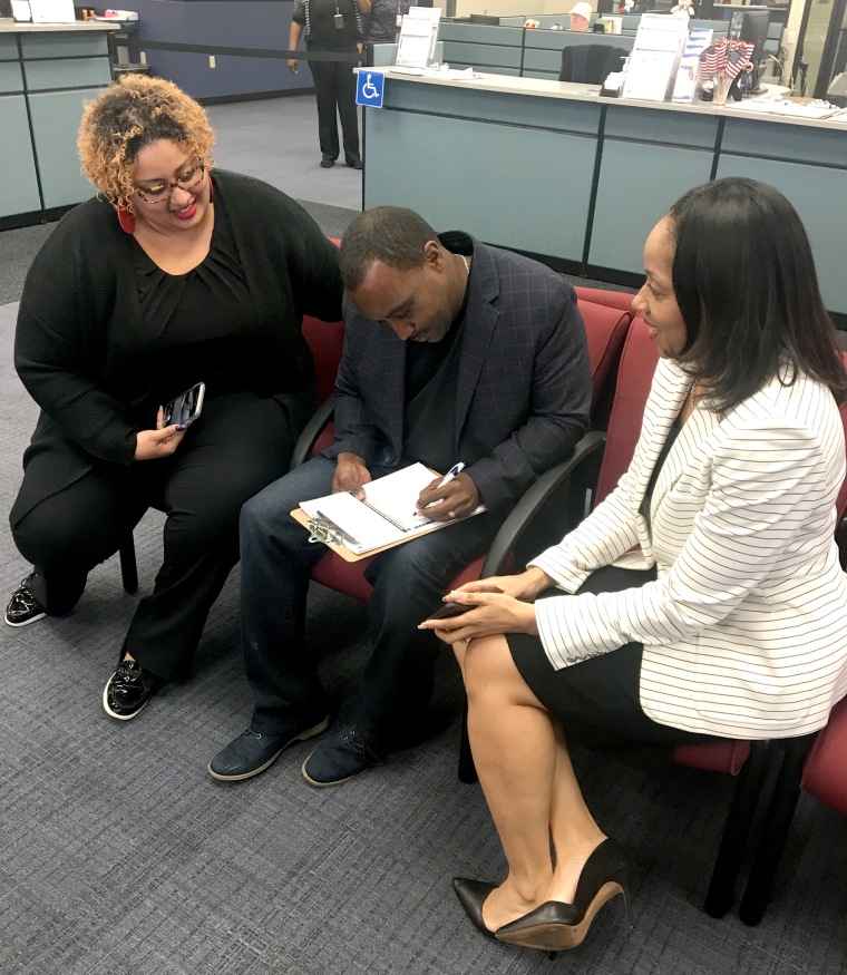 David Ayala is joined by his sister, Mariely Feraro, left, and his wife, state attorney Aramis Ayala, as he fills out his voter registration card at the Orange County Supervisor of Elections in Orlando, Florida, on Jan. 8, 2019.