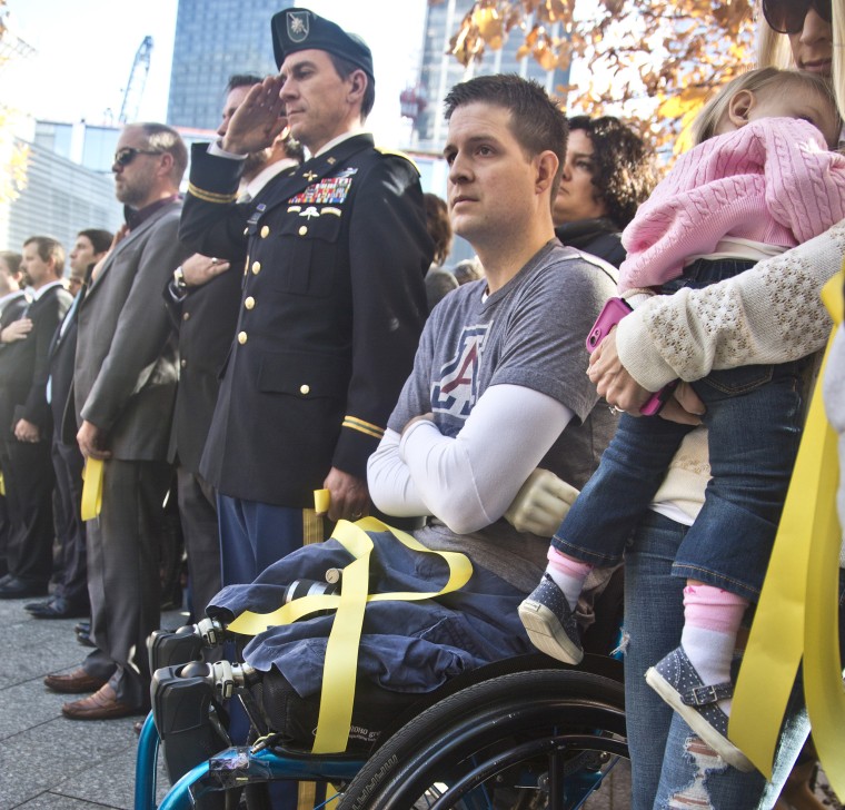 Former U.S. Air Force Senior Airman Brian Kolfage, center, sits in a wheelchair next to his wife Ashley, right, who holds their daughter Paris, during the National September 11 Memorial and Museum's "Salute to Service" tribute honoring U.S. veterans in New York on Nov. 10, 2014.