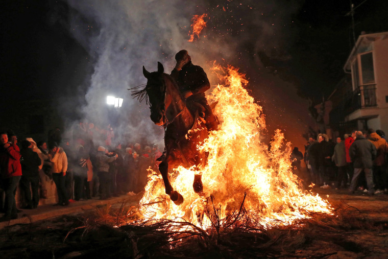 Image: A rider goes through flames during the annual \"Luminarias\" celebration northwest of Madrid