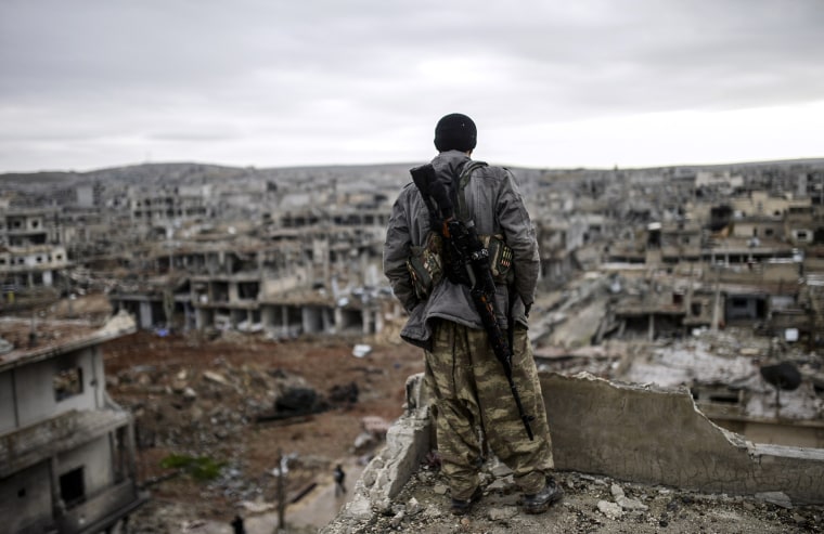 Musa, a 25-year-old Kurdish marksman, stands atop a building as he looks at the destroyed Syrian town of Kobane