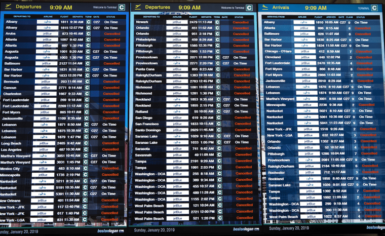 A flight information display shows cancelled flights at Logan International Airport