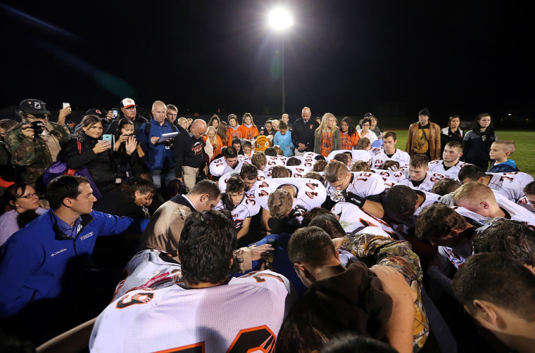 Image: Bremerton assistant football coach Joe Kennedy, obscured at center in blue, is surrounded by players in prayer in Bremerton, Washington, on Oct. 16, 2015.