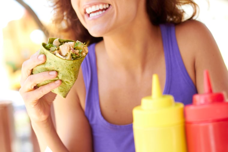 Image: Woman Holding Chicken Wrap in a green spinach tortilla