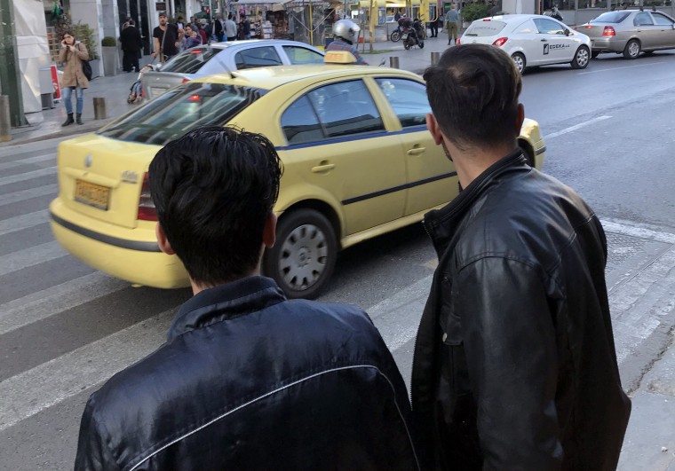 Fazul, left, crosses a street in central Athens alongside Khasim