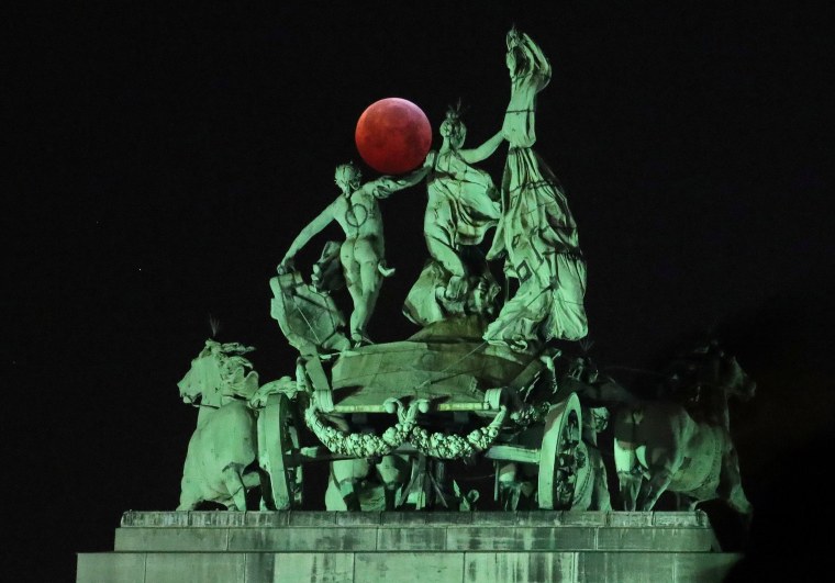 Image: The moon is seen beside a quadriga on the top of the Cinquantenaire arch during a total lunar eclipse known as the \"Super Blood Wolf Moon\", in Brussels