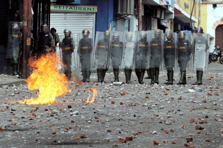 Image: Security forces look on while clashing with opposition supporters participating in a rally against Venezuelan President Nicolas Maduro's government